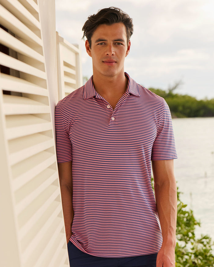The lifestyle view of the Southern Tide Coastal Breeze® Oceanfront Stripe Pique Performance Polo by Southern Tide - Sea Pink