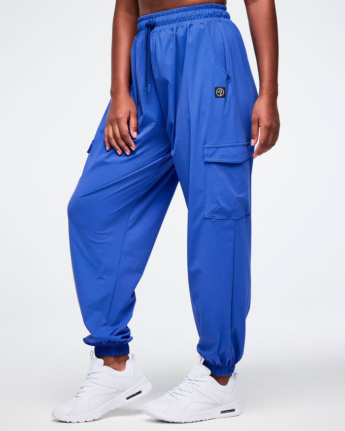 Female model wearing blue cargo pants on a white background.