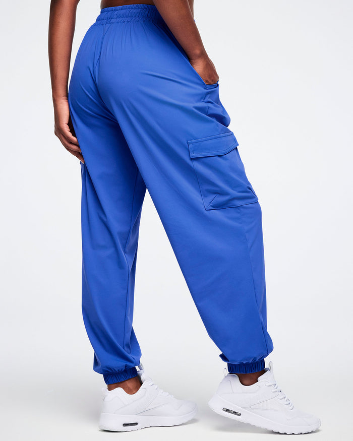 Back view of a female model wearing blue cargo pants on a white background.