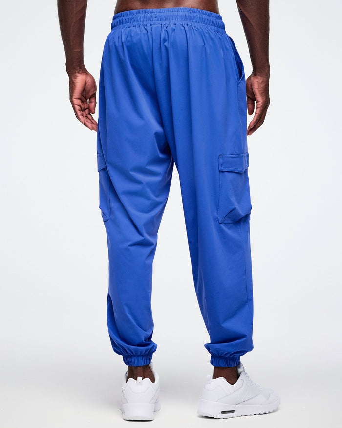 Back view of male model wearing blue cargo pants worn with white shoes.