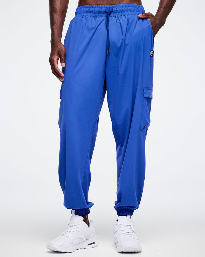 Male model with his hand in the left pocket of the blue cargo pants worn by a person on a white background.