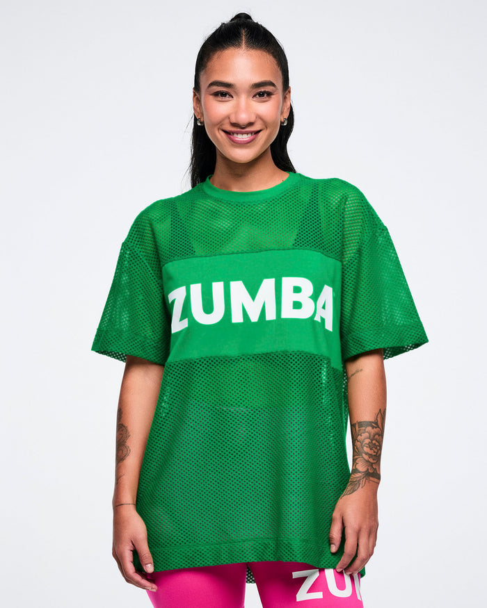 Female model wearing a green mesh Zumba top on a white background.