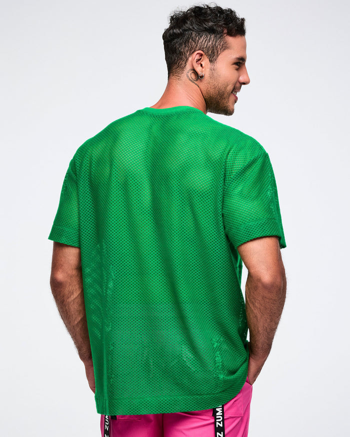 Back view of a male model wearing a green mesh top with pink pants on a white background.