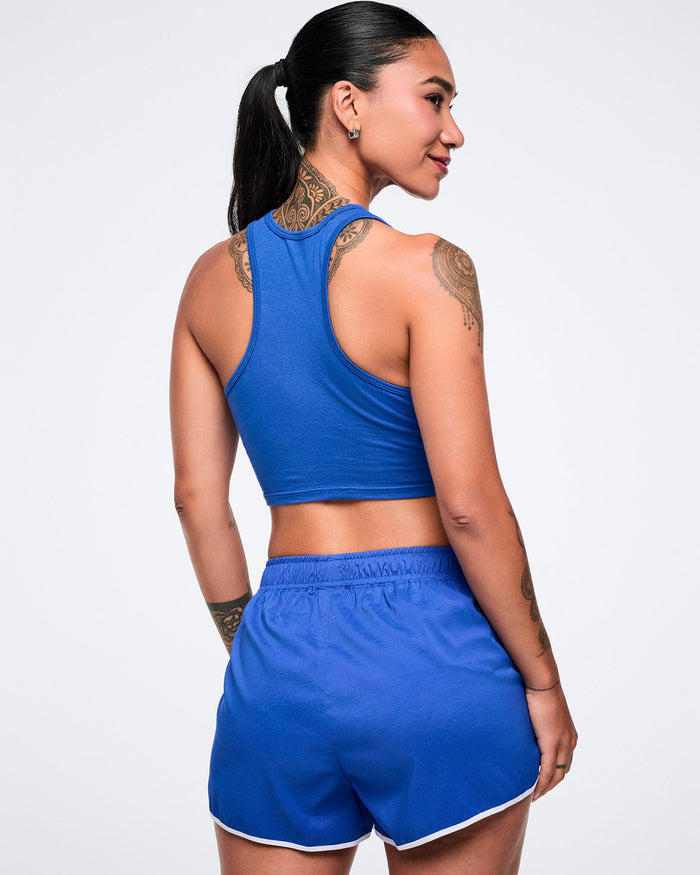 Back view of a female model wearing a blue crop racerback and matching shorts.