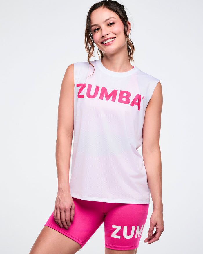 Female model in a mesh crew neck muscle tank featuring pink "Zumba" lettering, paired with pink shorts.
