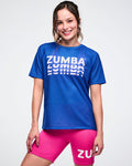 Female model wearing a blue Zumba mesh top and pink shorts on a white background.