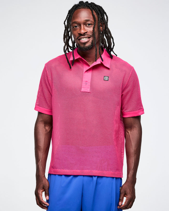 Male model wearing a pink mesh polo shirt with a small logo and blue pants against a white background.