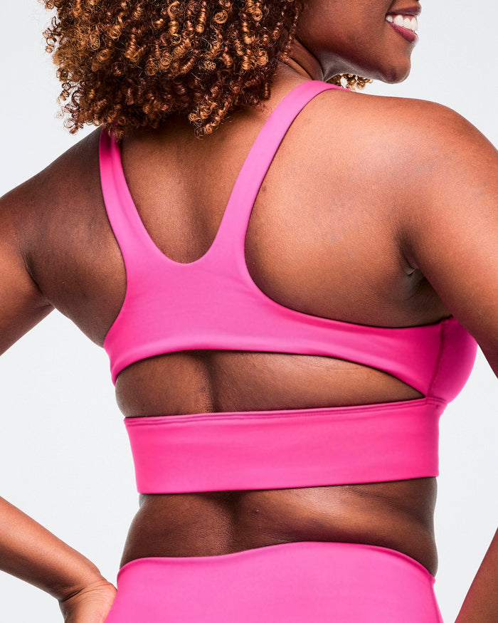 Close-up back view of a pink scoop neck bra worn by a female model, against a white background.