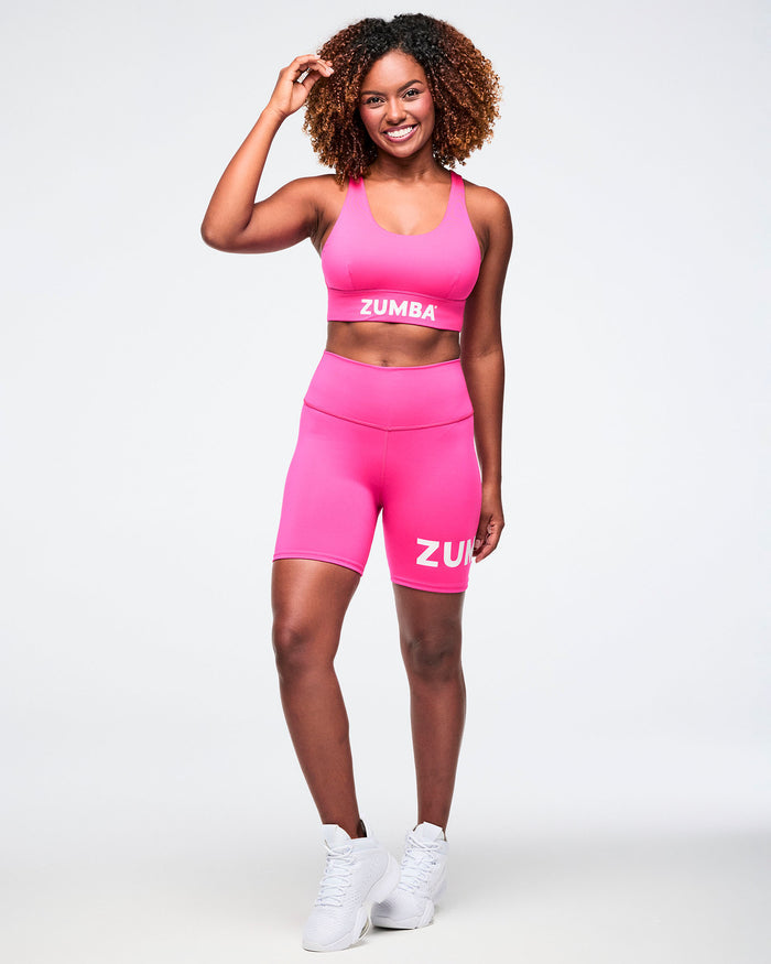 Female model full body view wearing a  matching pink Zumba outfit.