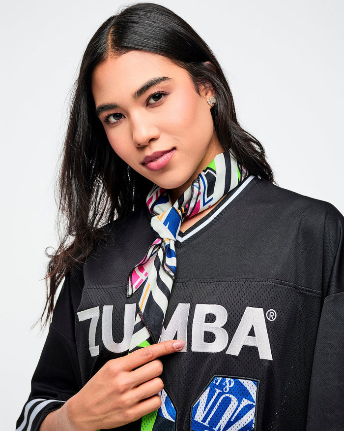 Female model wearing a black Zumba top with a colorful bandana tied around her neck on a white background.