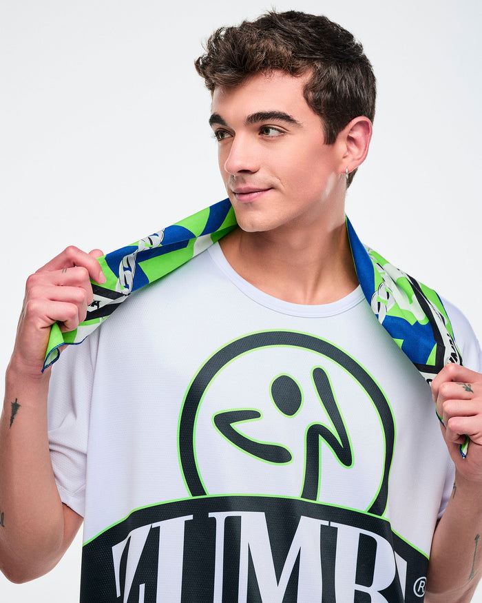 Male model holding a blue, white, and green bandana around his shoulders, wearing a white tee with “ZUMBA” in large letters.