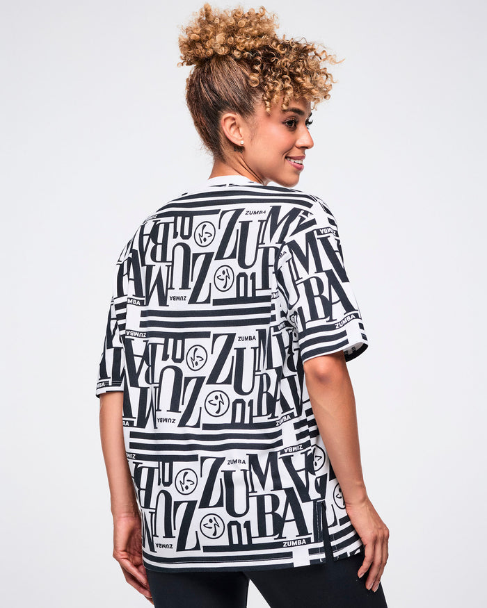 Back view of a female model wearing a black and white patterned Zumba boxy top.