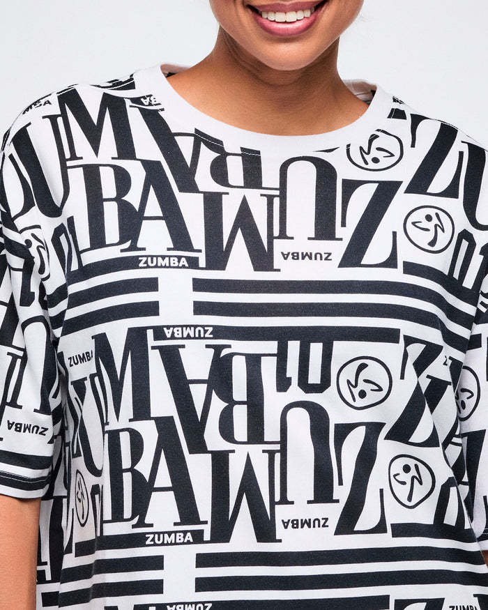 Close-up of a female model wearing a black and white patterned Zumba boxy top.