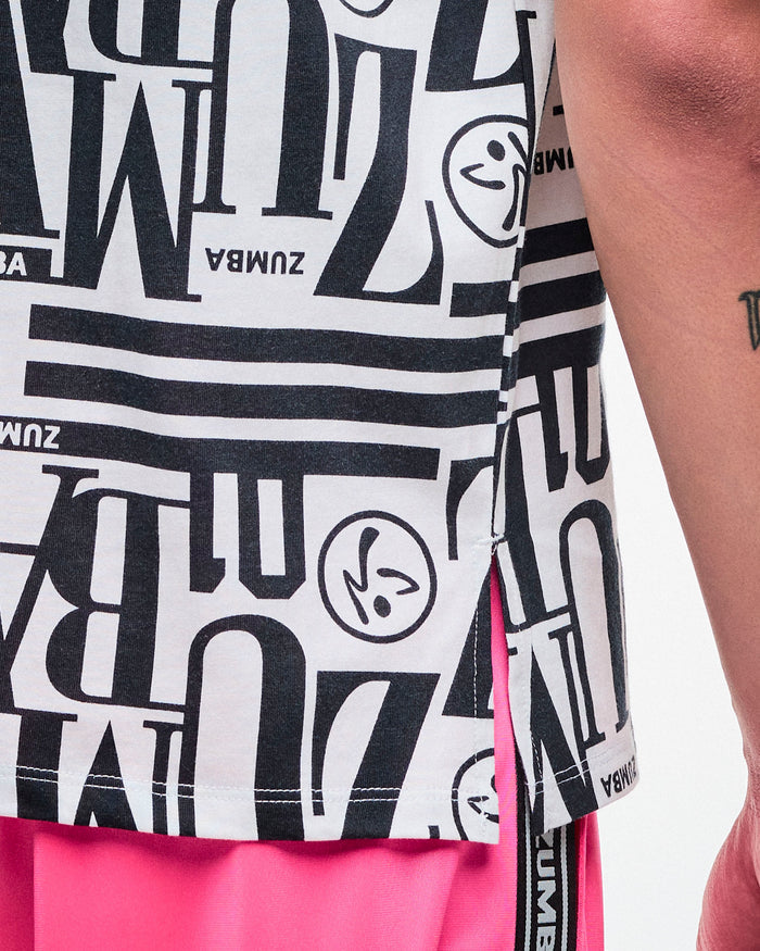 Close-up of a male model in a black-and-white patterned Zumba boxy top, highlighting the side slits, paired with pink pants.