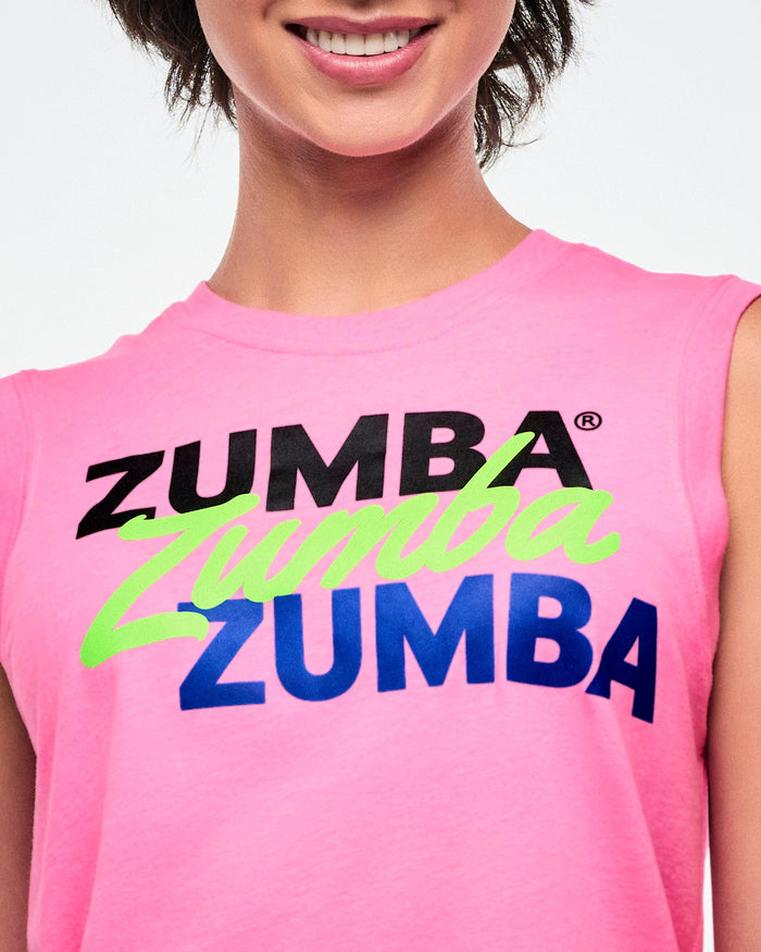 Close-up view of a female model wearing a pink Zumba tank top with black, green and blue ZUMBA text.