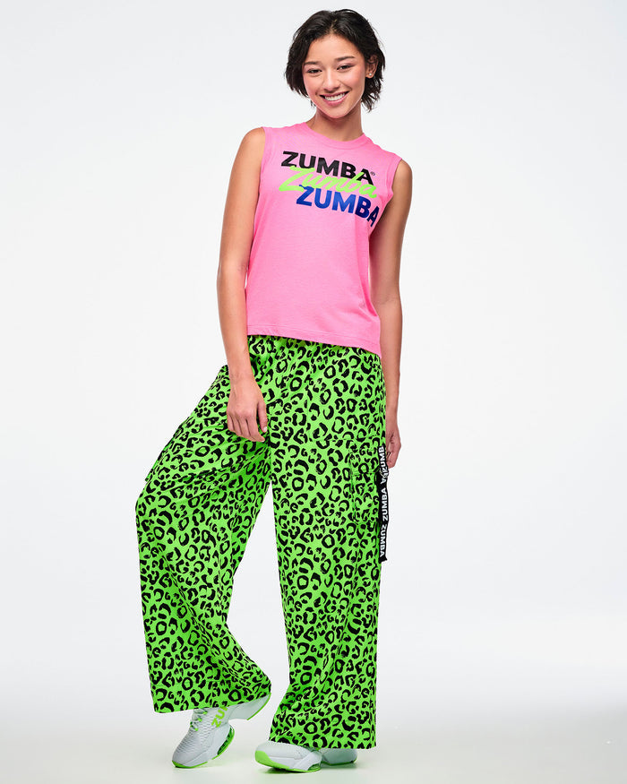 Female model wearing a pink Zumba tank and green leopard print pants on a white background.