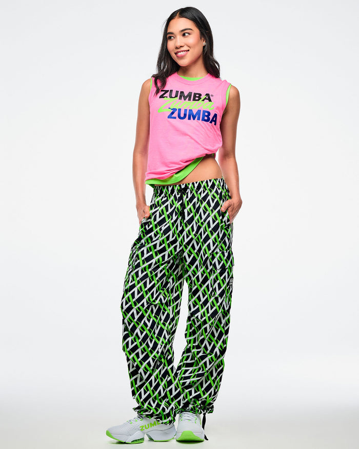 Female model wearing a Zumba tank top and patterned pants paired with white and green shoes.