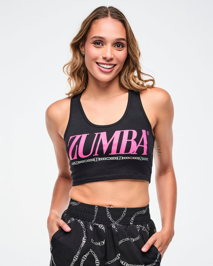 Female model wearing a black Zumba sports bra and black pants with white patterns on a light background.