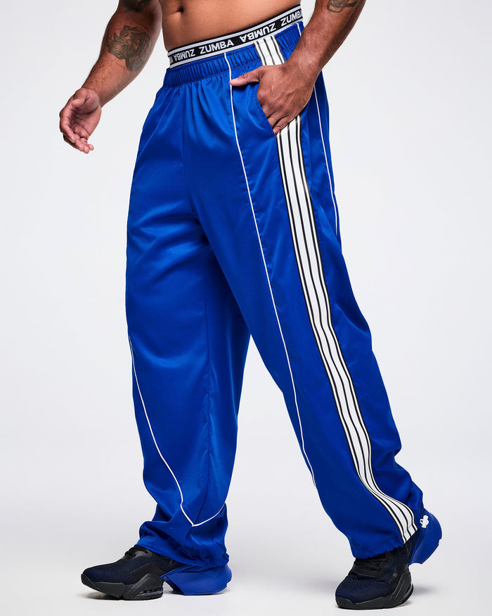Male model with one hand in the pocket of blue woven pants, paired with blue-and-black shoes.