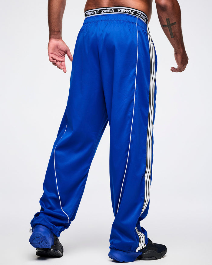Back view of a male model wearing blue woven pants, paired with blue-and-black shoes.