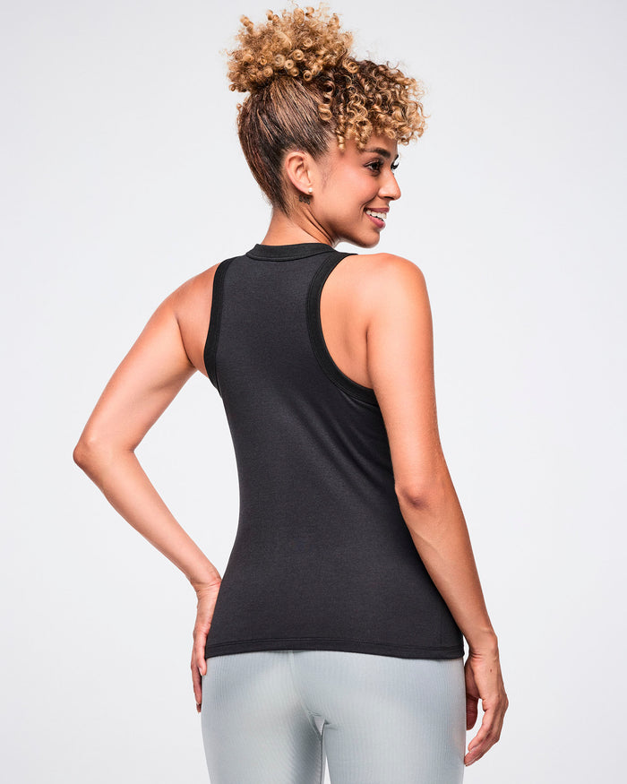 Back view of a female model wearing a black tank top paired with silver biker shorts.