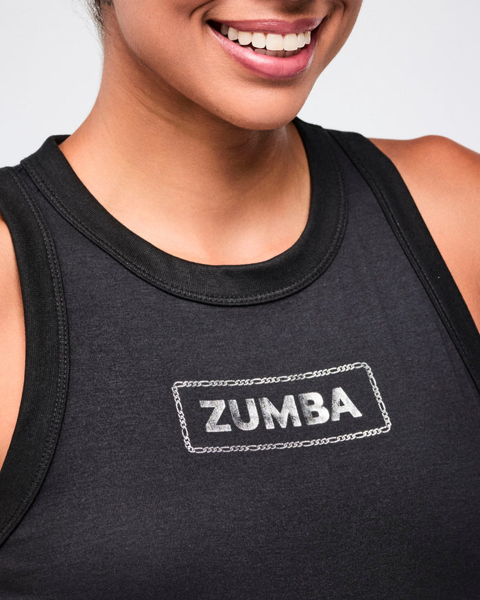 Close-up detailed view of a female model wearing a black tank top with a detailed view of the silver 'Zumba' logo on the chest.