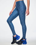 Female model in blue denim-print leggings with “ZW, 01, dots, Zumbito” pattern, blue-black shoes, on a white background.