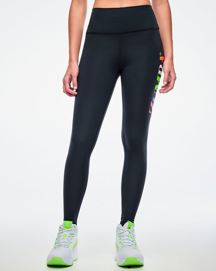 Front view of a female model wearing black Zumba leggings paired with green-and-white shoes.