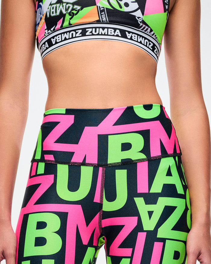 Close-up detailed view of black-base leggings featuring green and pink “ZUMBA” patterned lettering on a white background.
