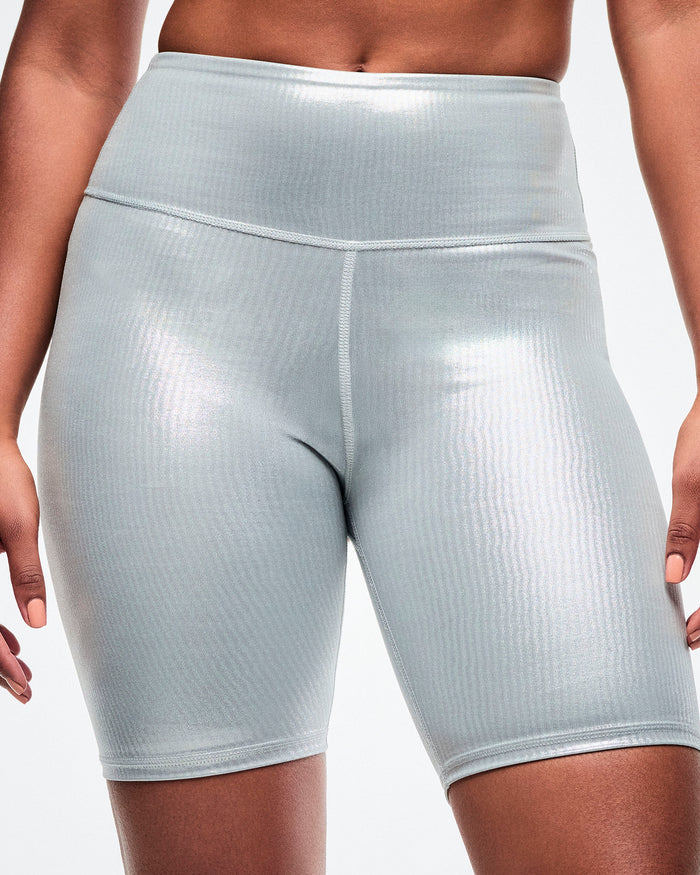 Silver ribbed biker shorts worn by a female model on a white background.