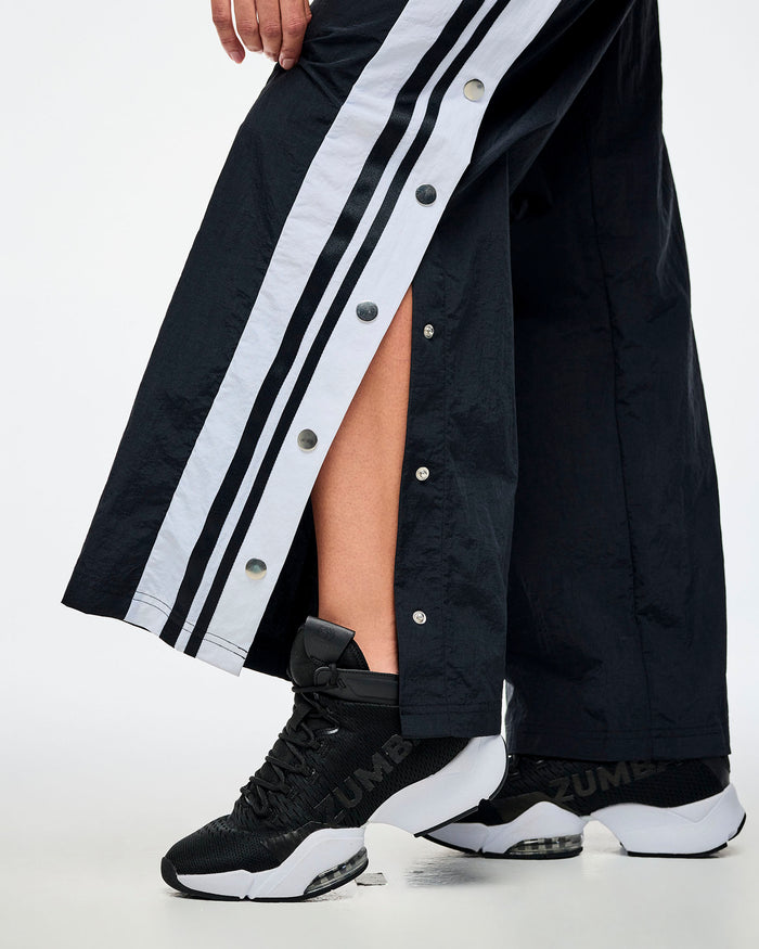 Detailed close-up view of black and white pants with the side snap buttons in detail and paired with black and white shoes.