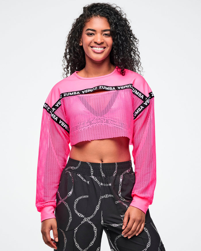 Female model wearing a pink Zumba crop top and black patterned pants on a white background.