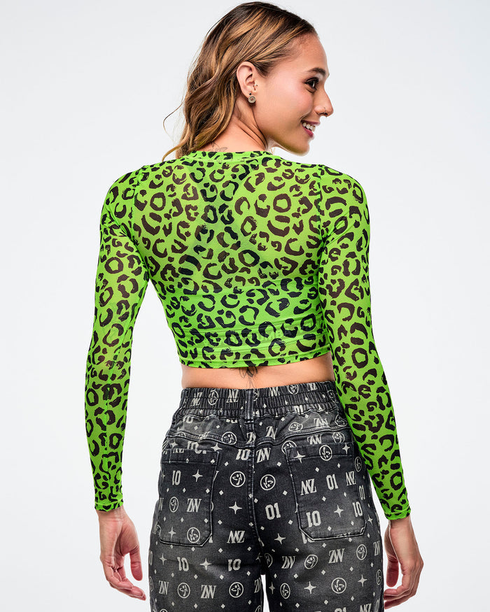 Back view of a female model wearing a green leopard print mesh crop top and black patterned denim jorts on a white background.