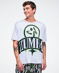 Male model wearing a white Zumba top with black and green Zumba logo on a plain background.