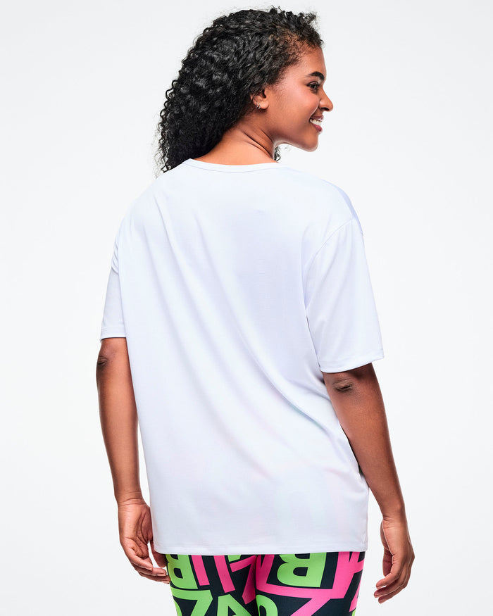 Back view of a female model in a white Zumba top against a white background.