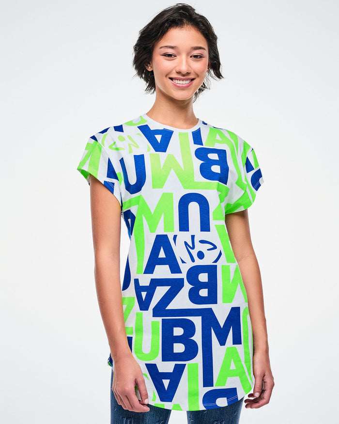 Female model wearing a colorful t-shirt with "ZUMBA" letter patterns on a plain background.