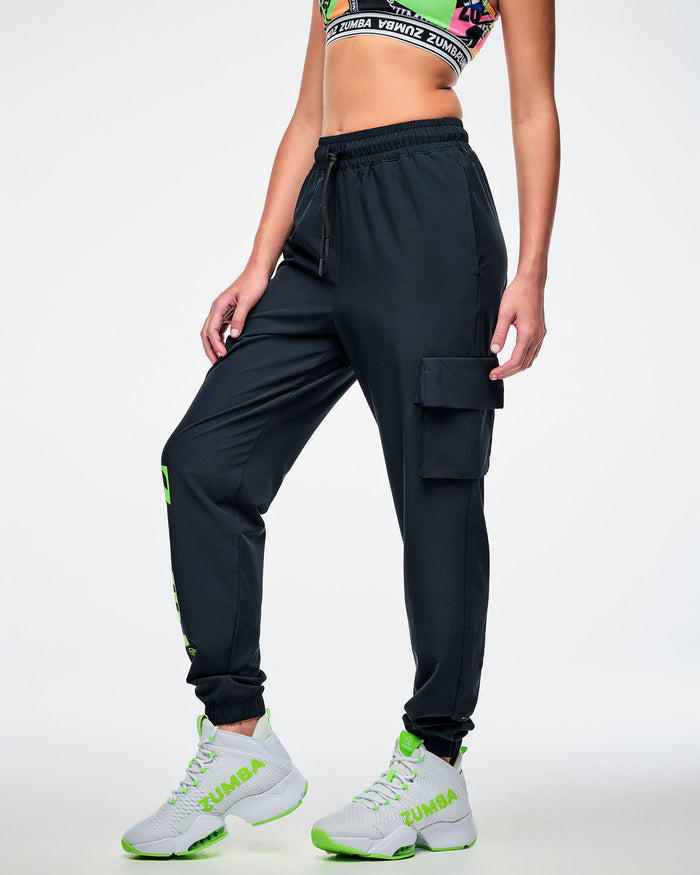 Female model wearing black cargo pants, showcasing the left-leg cargo pocket, paired with green-and-white shoes.