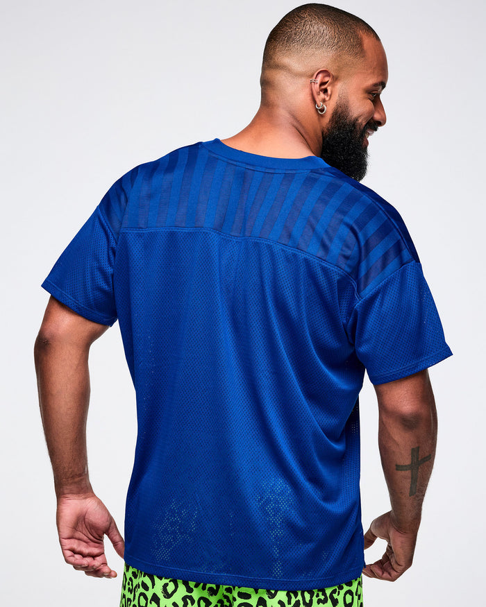 Back view of a male model wearing a blue mesh jersey with green leopard pants.