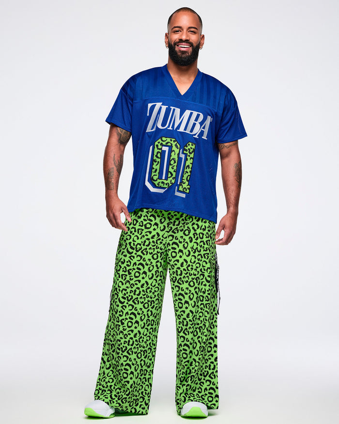 Male model wearing a blue jersey with 'ZUMBA 01' print paired with green leopard pants and green and white shoes.