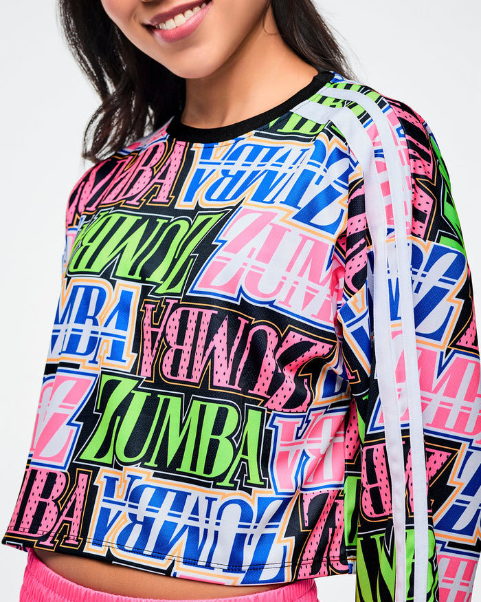 Close-up view of a female model wearing a colorful Zumba boxy crop top.