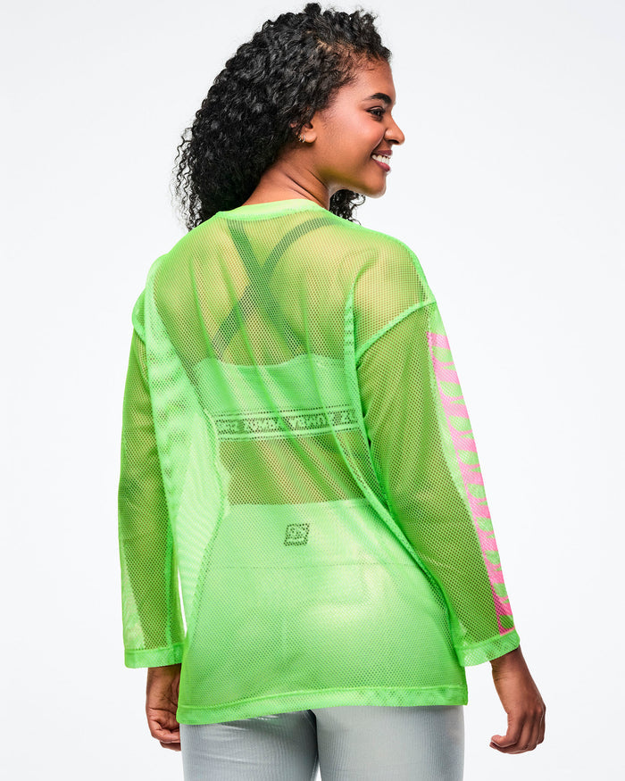 Back view of a female model wearing a neon green mesh Zumba top paired with silver biker shorts.