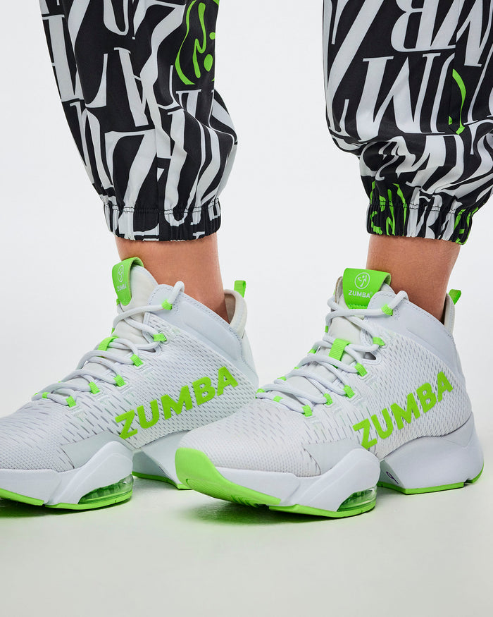 Close-up of the encased elastic cuffs on black-and-white patterned Zumba pants with green Zumbito accents, paired with green-and-white shoes.