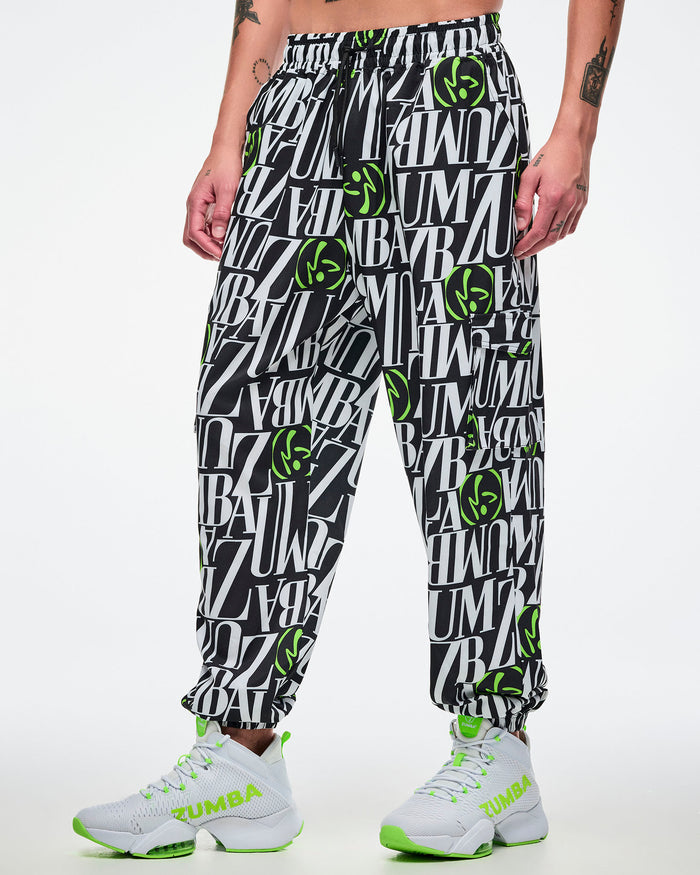 Male model wearing black and white patterned pants with green Zumbito accents on a white background.