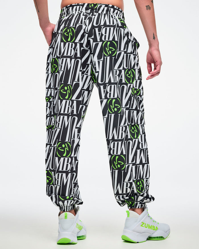 Back view of a male model wearing black and white patterned pants with green Zumbito accents on a white background.