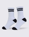 A pair of white crew socks with black accents, featuring the brand name 'ZUMBA' printed in white on a black band around the ribbed ankle cuffs, set against a light gray background.