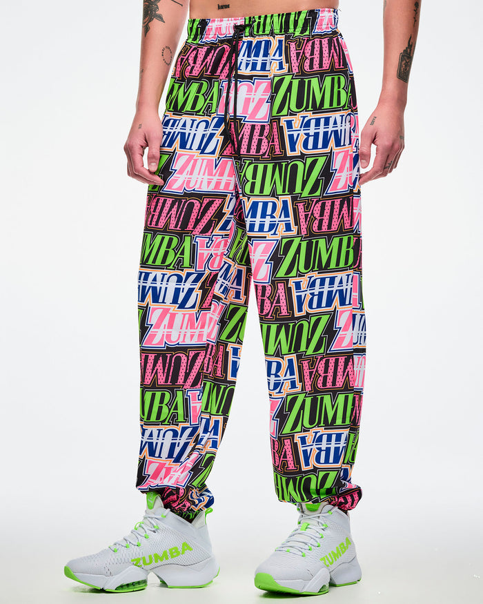 Male model wearing multicolored woven pants paired with white and green shoes.