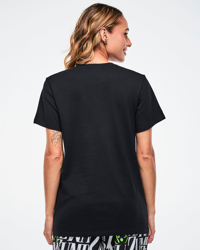 Back view of a female model wearing a black Zumba tee on a white background.