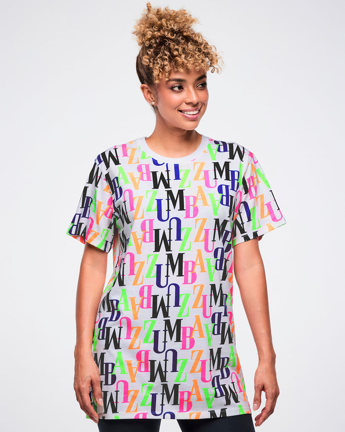 Female model wearing a colorful 'ZUMBA' patterned t-shirt against a white background.
