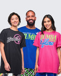 Three models wearing Zumba branded t-shirts in black, blue and pink on a plain background.