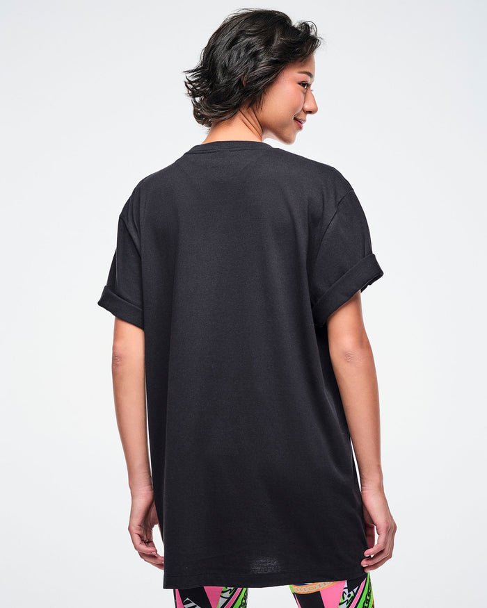Back view of a female model wearing a black Zumba t-shirt on a white background.